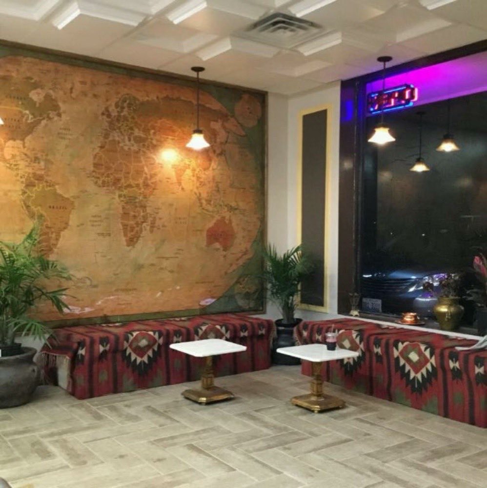 The dining room at Old School, with a painted world-map wall and set tables.